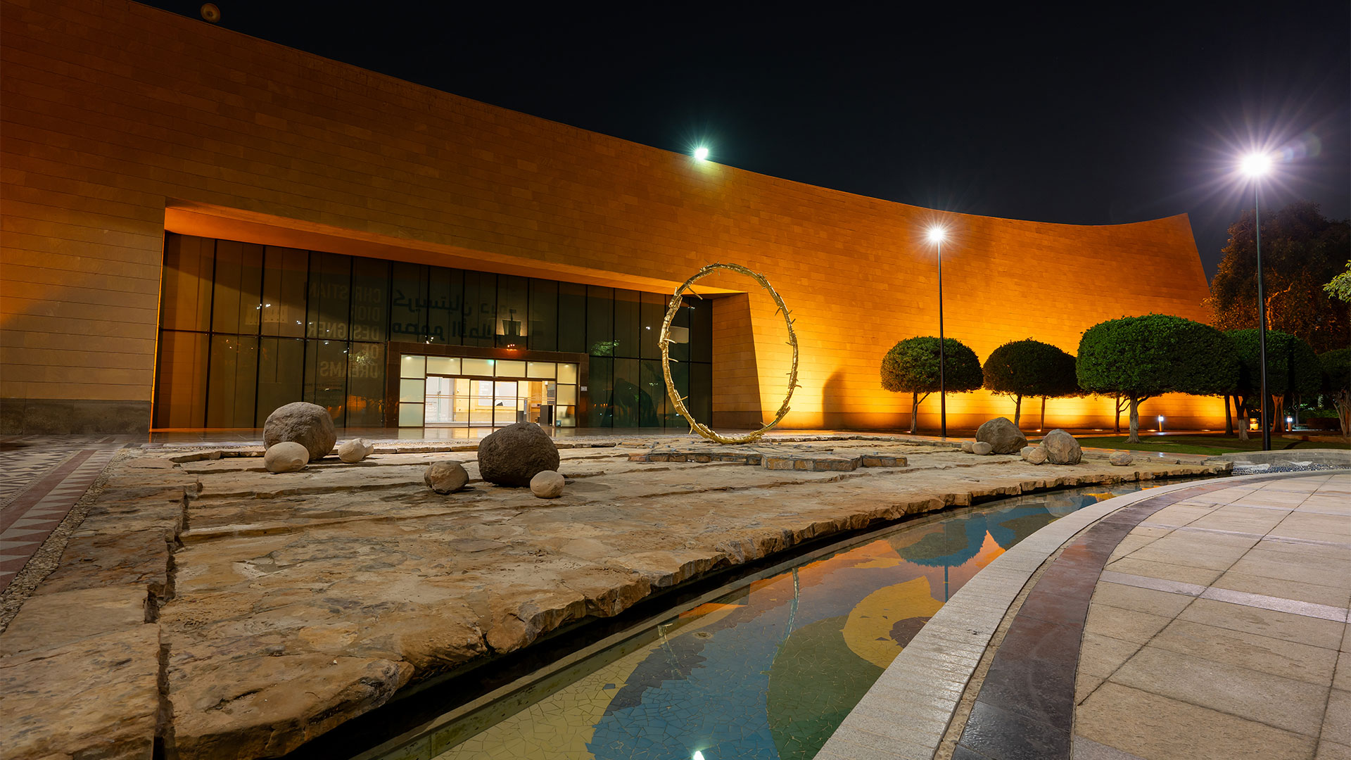 A large, bright yellow circular sculpture by Ugo Rondinone, titled the sun, installed in an open public space in Riyadh.