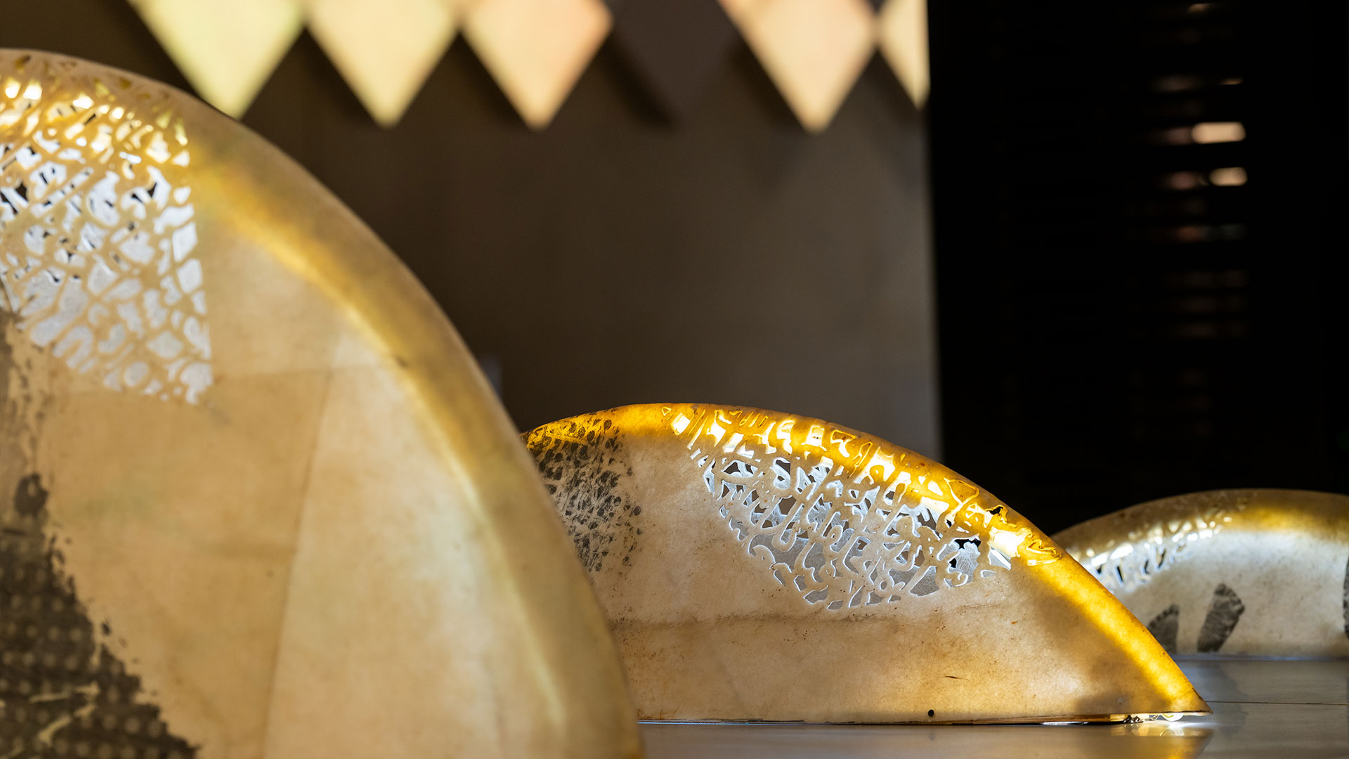 A poetic mixed media installation by Zaman Jassim, titled When the Moon is Full, featuring holographic light, Arabic calligraphy, and layered visual elements evoking memory and departure.