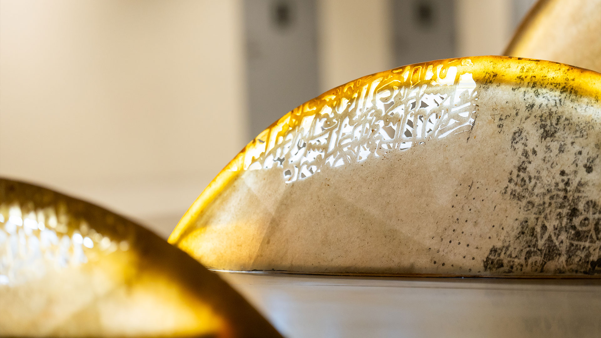 A poetic mixed media installation by Zaman Jassim, titled When the Moon is Full, featuring holographic light, Arabic calligraphy, and layered visual elements evoking memory and departure.