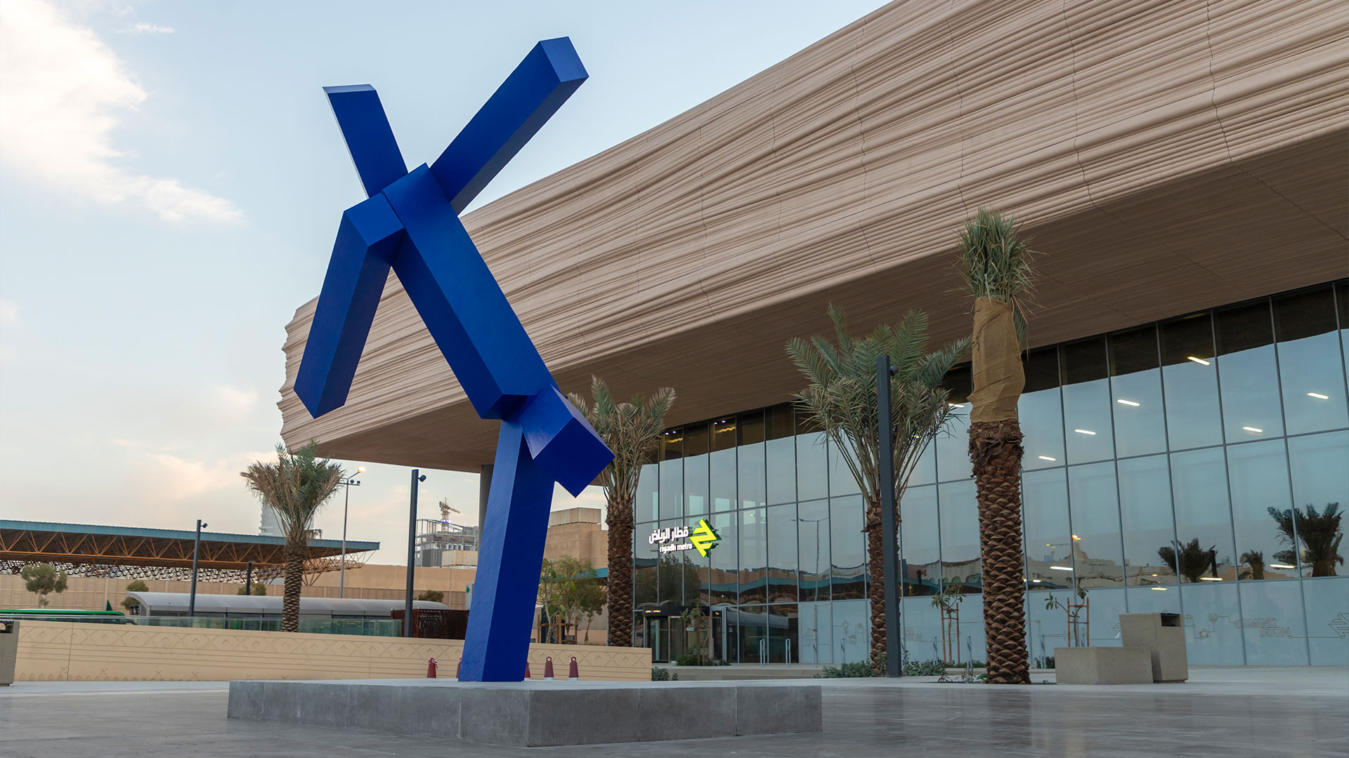 An abstract bronze sculpture by Joel Shapiro, titled Untitled, featuring angular forms that suggest a human figure in motion, installed outdoors in Riyadh.