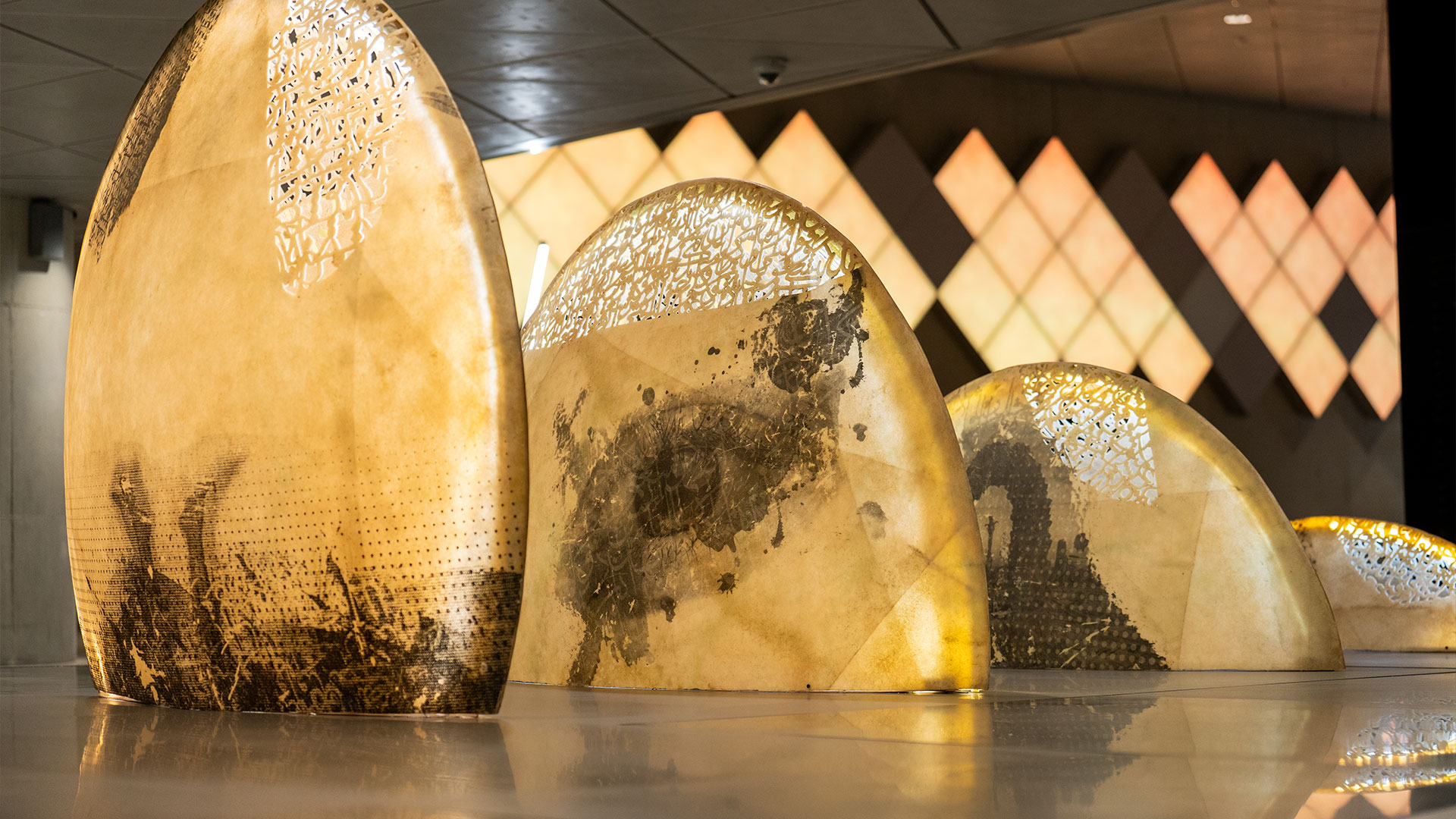 A poetic mixed media installation by Zaman Jassim, titled When the Moon is Full, featuring holographic light, Arabic calligraphy, and layered visual elements evoking memory and departure.