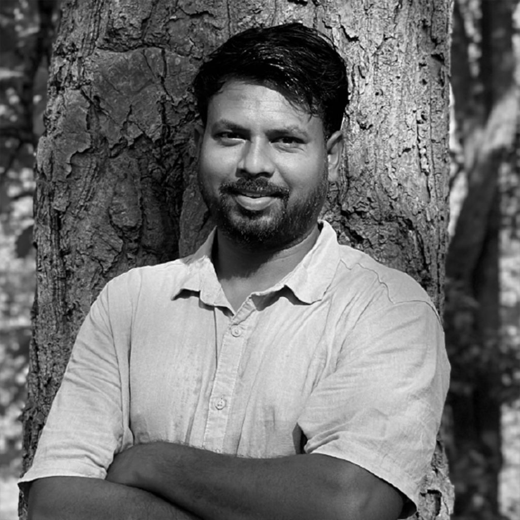 Portrait of Vankhade Sangam (b. 1991), Indian sculptor, standing beside one of his carved stone works. Known for exploring memory, empire, and material heritage through traditional craftsmanship and contemporary form.